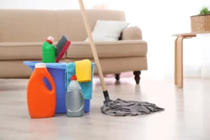 assortment of floor cleaning supplies on wood flooring, with a couch in the background