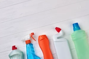 assortment of cleaning chemical bottles laid out on white wooden flooring
