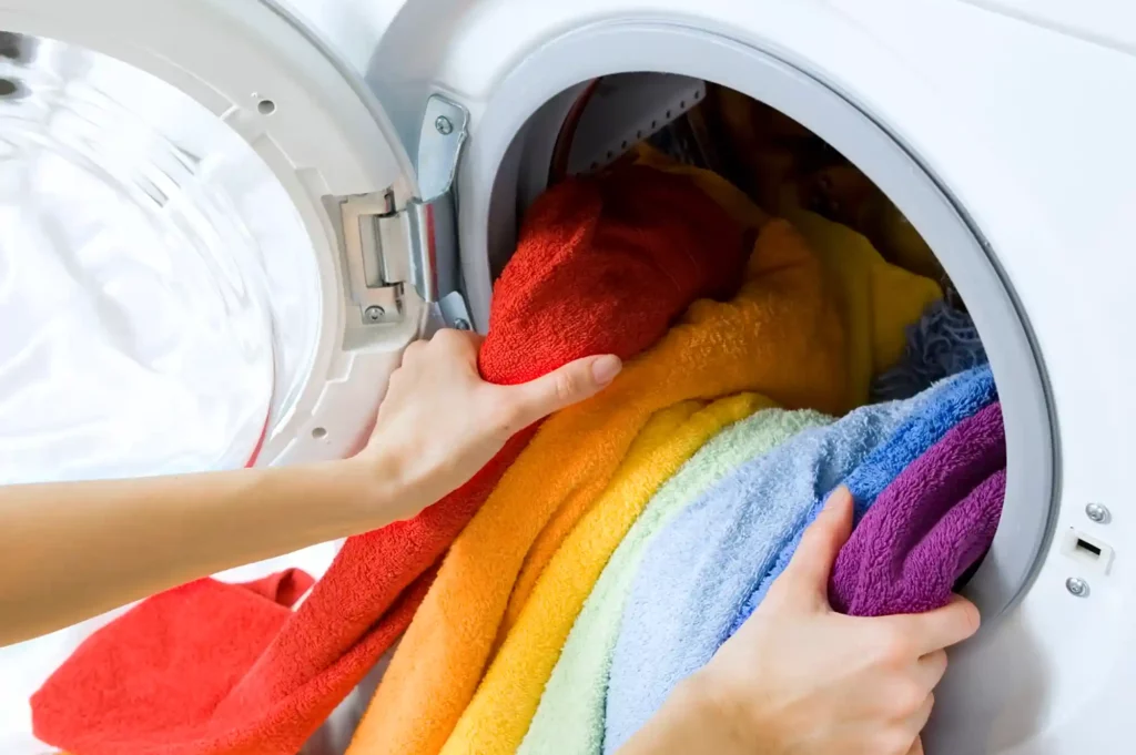 person pulling out clothes from washing machine