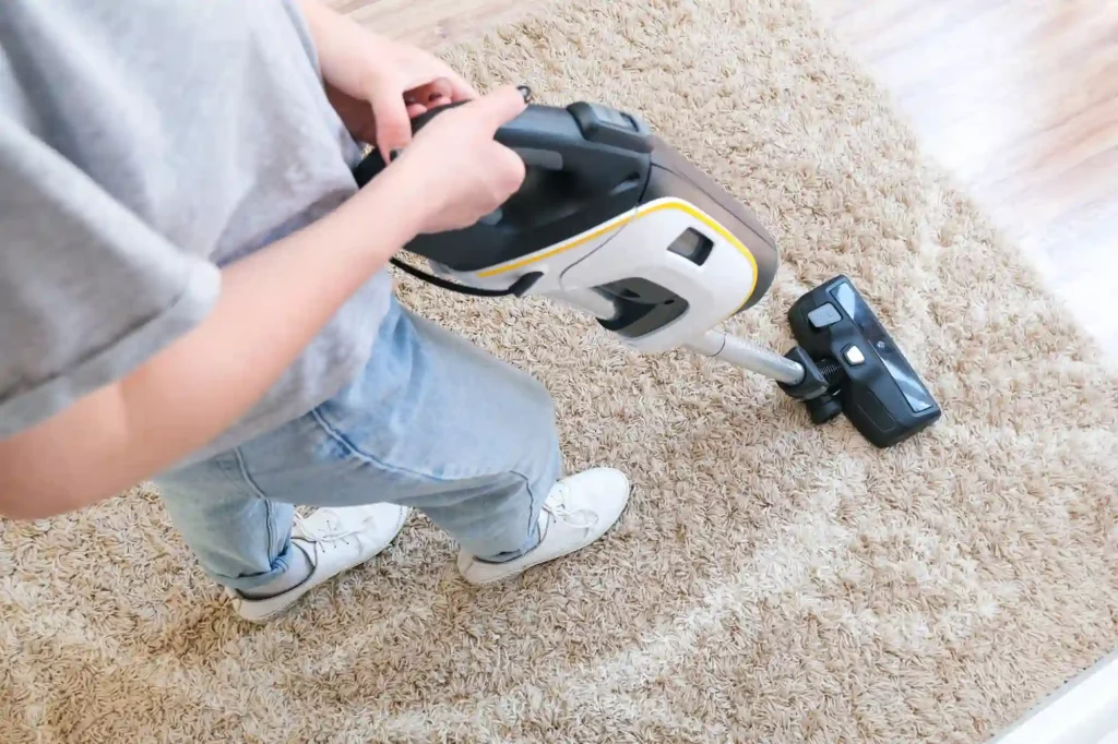 guy using upright hoover to vacuum rug