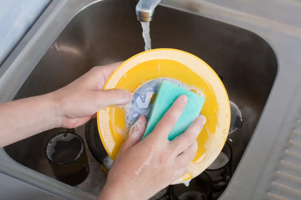Person cleaning yellow iron pan with scouring pad