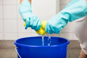 person wearing blue gloves cleaning a yellow microfibre cloth