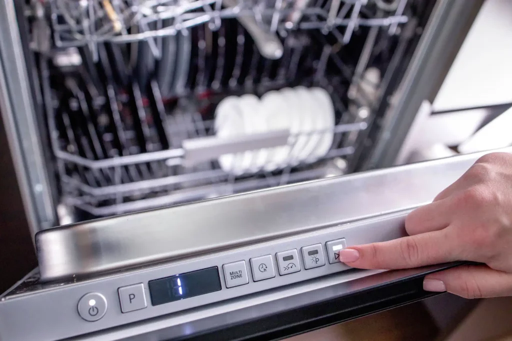 person pressing on control panel on dishwasher