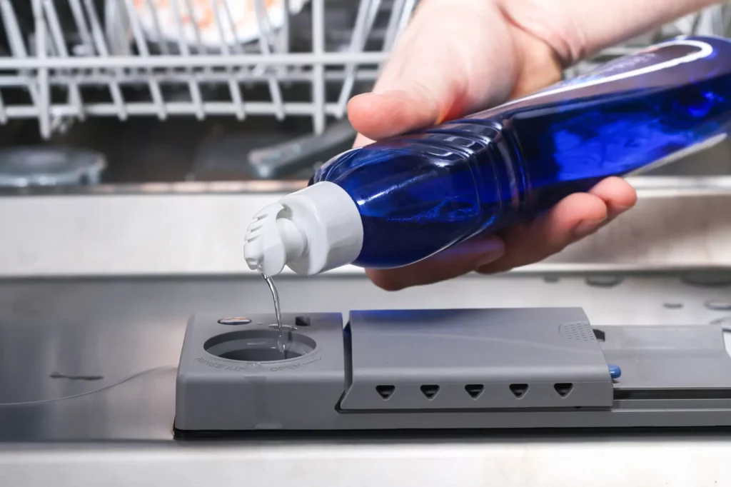 rinse aid being poured into a dishwasher